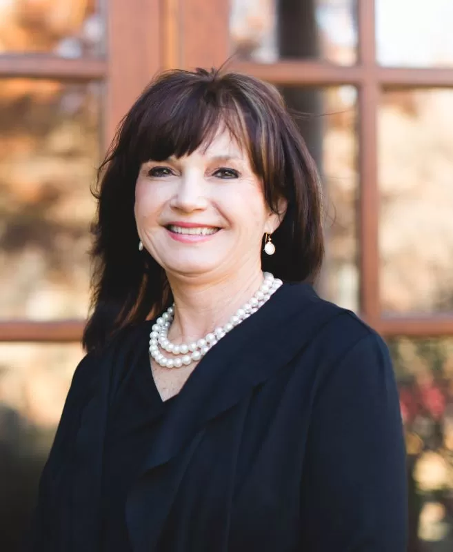 brunette woman in black wearing pearl necklace